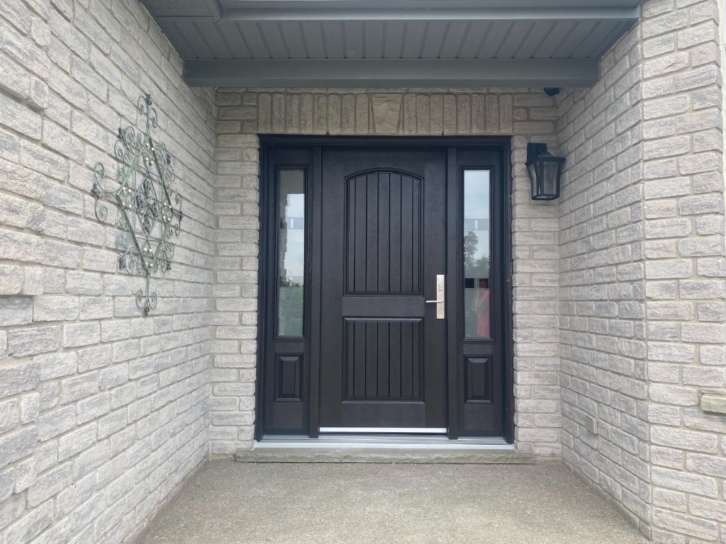 Dark entry door with sidelights installed in a stone entrance