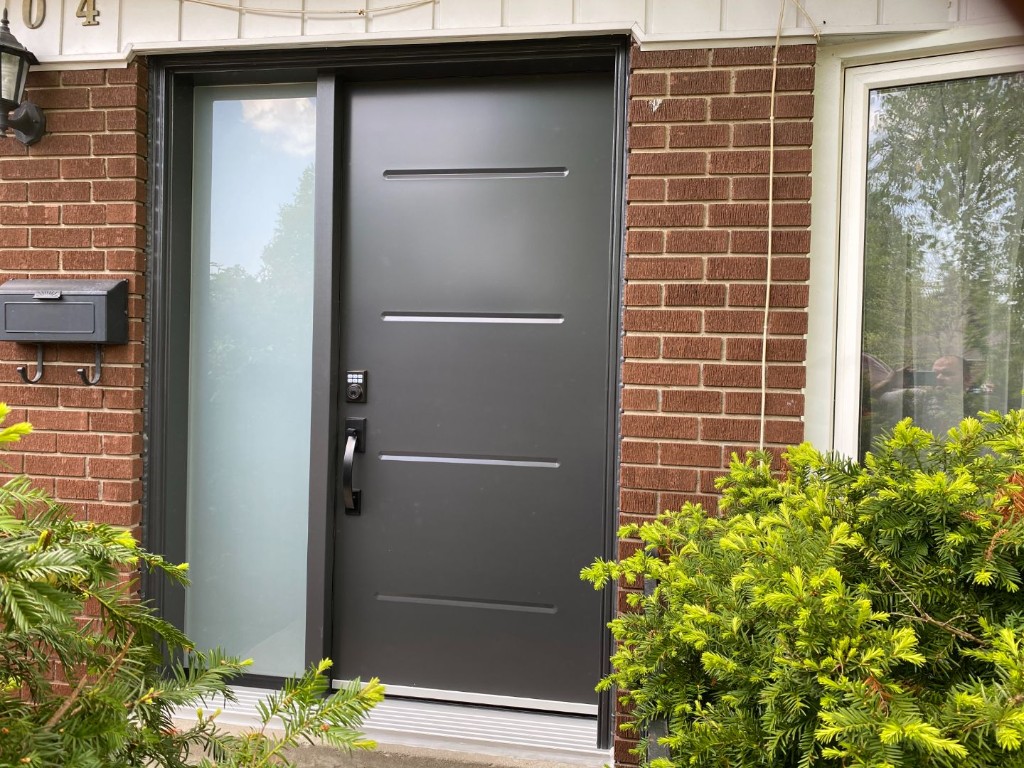Grey security entry door with an electronic lock beside a sidelight