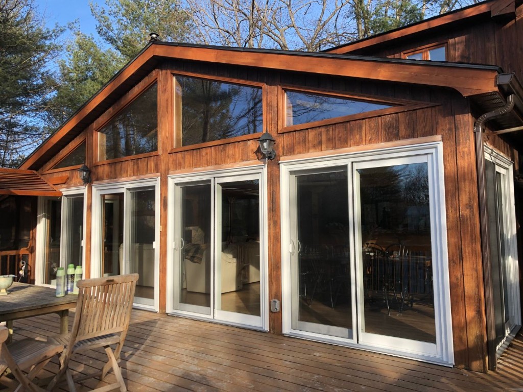 White sliding patio doors installed on a wood house