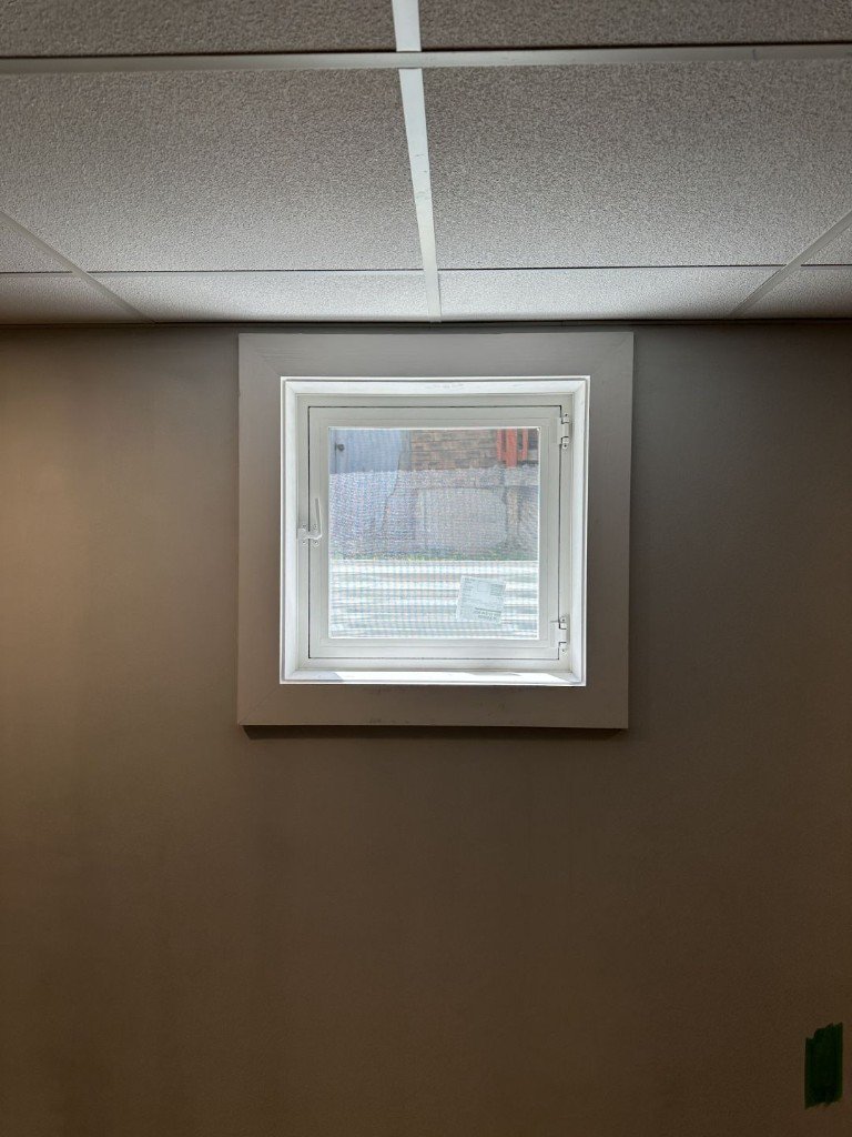 Finished white basement egress window set in an interior wall