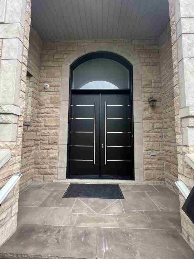 Contemporary black double doors with arched transom on stone entry Contemporary black double doors with arched transom on stone entry
