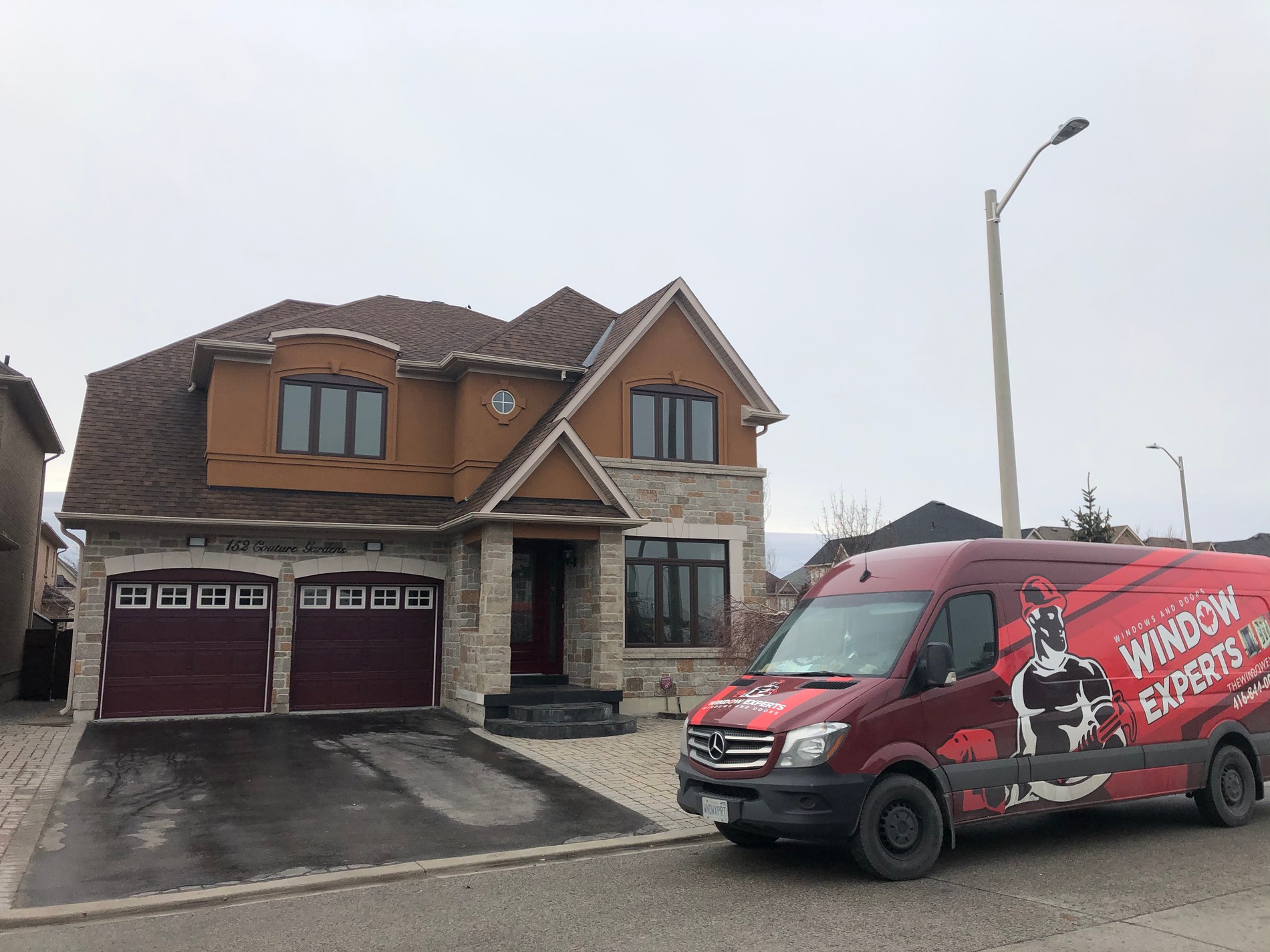 Red Window Experts van parked outside a two-story home with new windows and doors