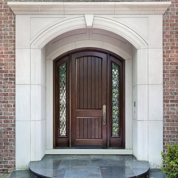 Arched wooden security door with leaded glass sidelights, framed by white stone and brick entryway